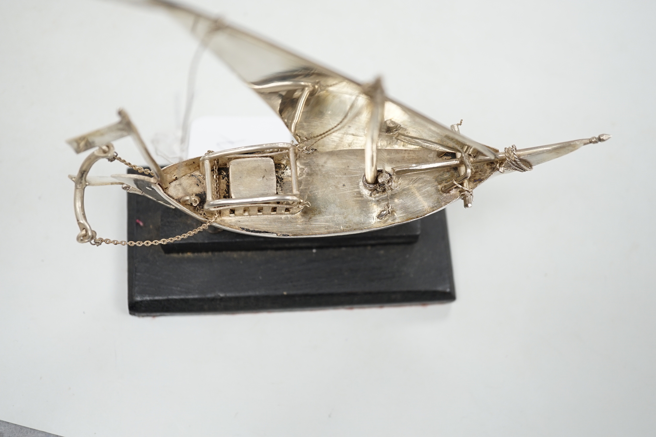 A Kuwait white metal miniature model of a sail boat, length 16cm, on wooden stand